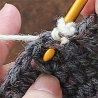 こま編み裏引き上げ編み[2] 後ろから針を入れたら、引き上げる目の手前を通ってもう一度裏に向かって針を入れます。