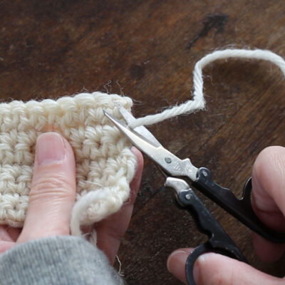 かぎ針編みの編み終わりと糸処理の風景。編み地、仕上げを待つ毛糸の道具たち
