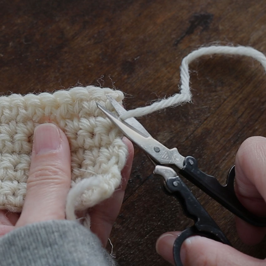 かぎ針編みの編み終わりと糸処理の風景。編み地、仕上げを待つ毛糸の道具たち