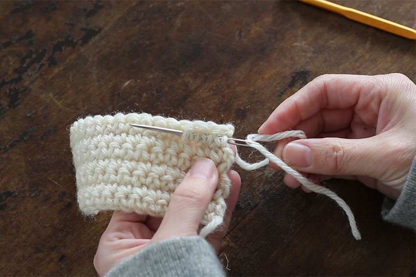[1] 糸の根本付近から、2～3cm編み地の中にとじ針をくぐらせます。