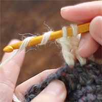 長々編み2目一度[5] 針に糸を2回巻き、前段のとなりの目に針を入れて、もう1つ未完成の長々編みを編みます。