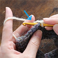 リング編み[2] 左手の中指で、毛糸を矢印の方向に押し下げます。