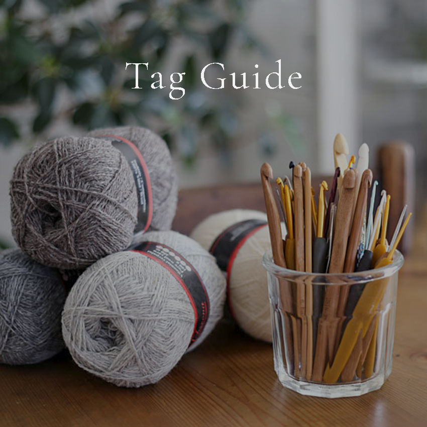 ガラス瓶に入った様々なかぎ針と毛糸の玉、'Tag Guide' の文字が入ったライフスタイル画像