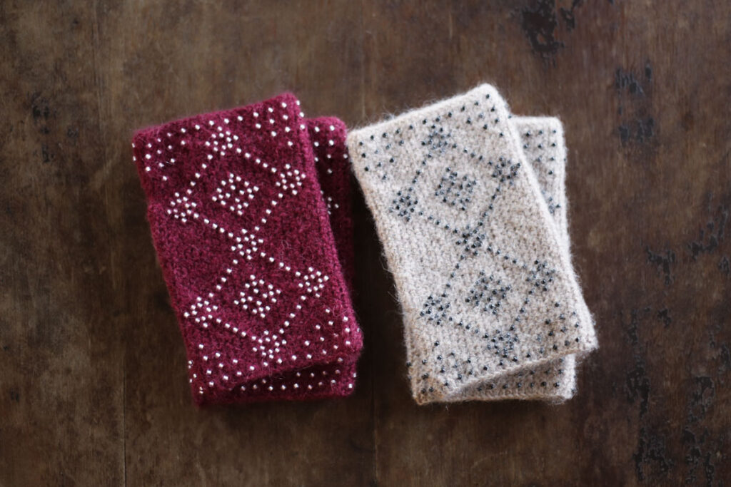 「すてきにハンドメイド 2022年12月号」（NHK出版）に掲載されたRonique デザインのビーズ編みハンドウォーマー作品。配色違いで2パターンを制作。