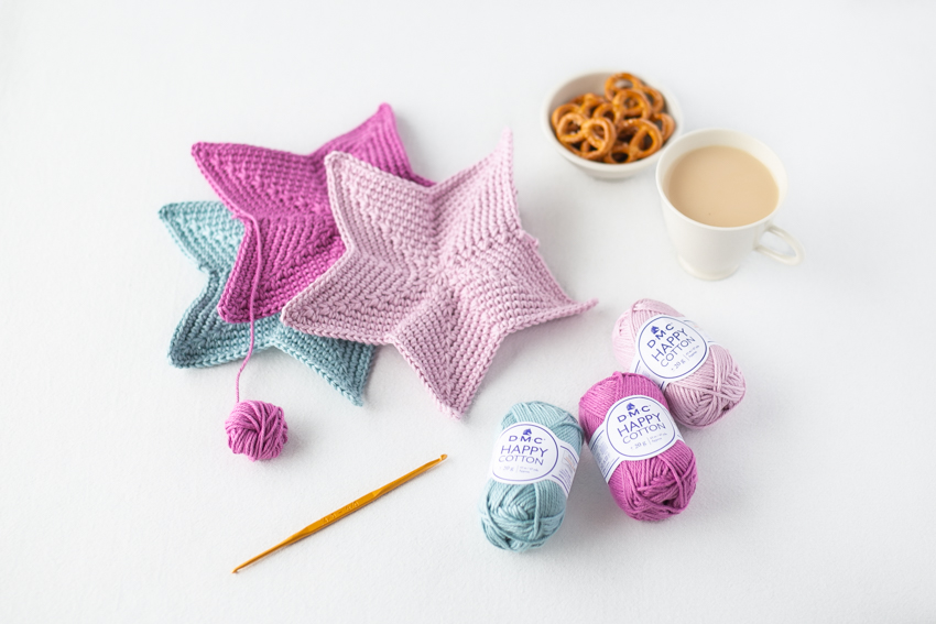 かぎ針編みのおやつマットやティータイムのコースターに。カラフルな色違い作品を編みかけている様子